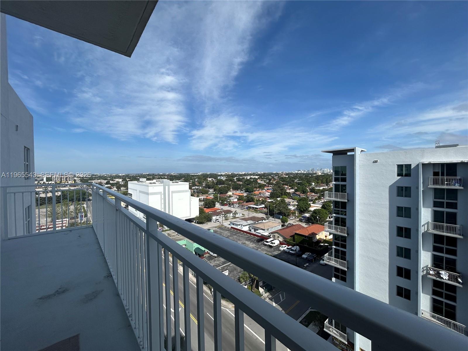 A high-angle view from a balcony overlooking a street, parking lot, and suburban neighborhood — 60 NW 37th Ave # 1205, Miami FL 33125, MIAMI, FL