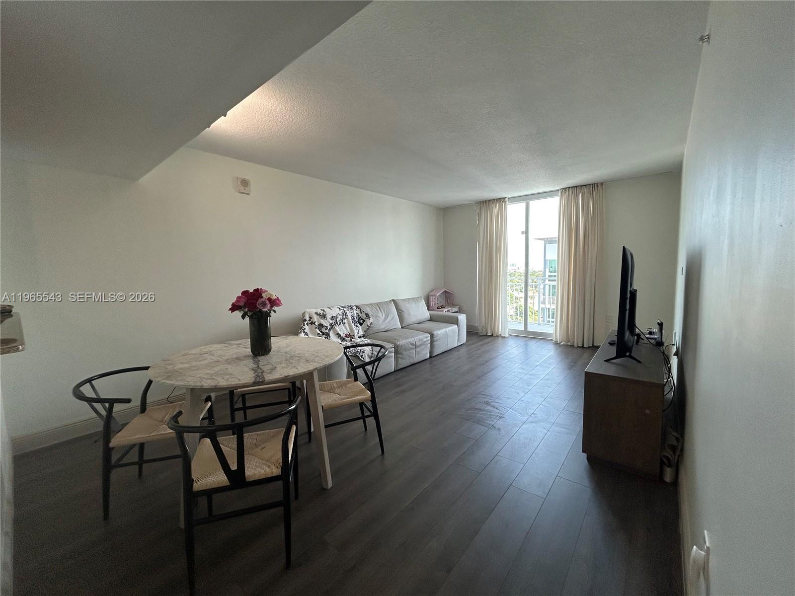 A living and dining area features dark wood flooring, a marble table, and a balcony — 60 NW 37th Ave # 1205, Miami FL 33125, MIAMI, FL