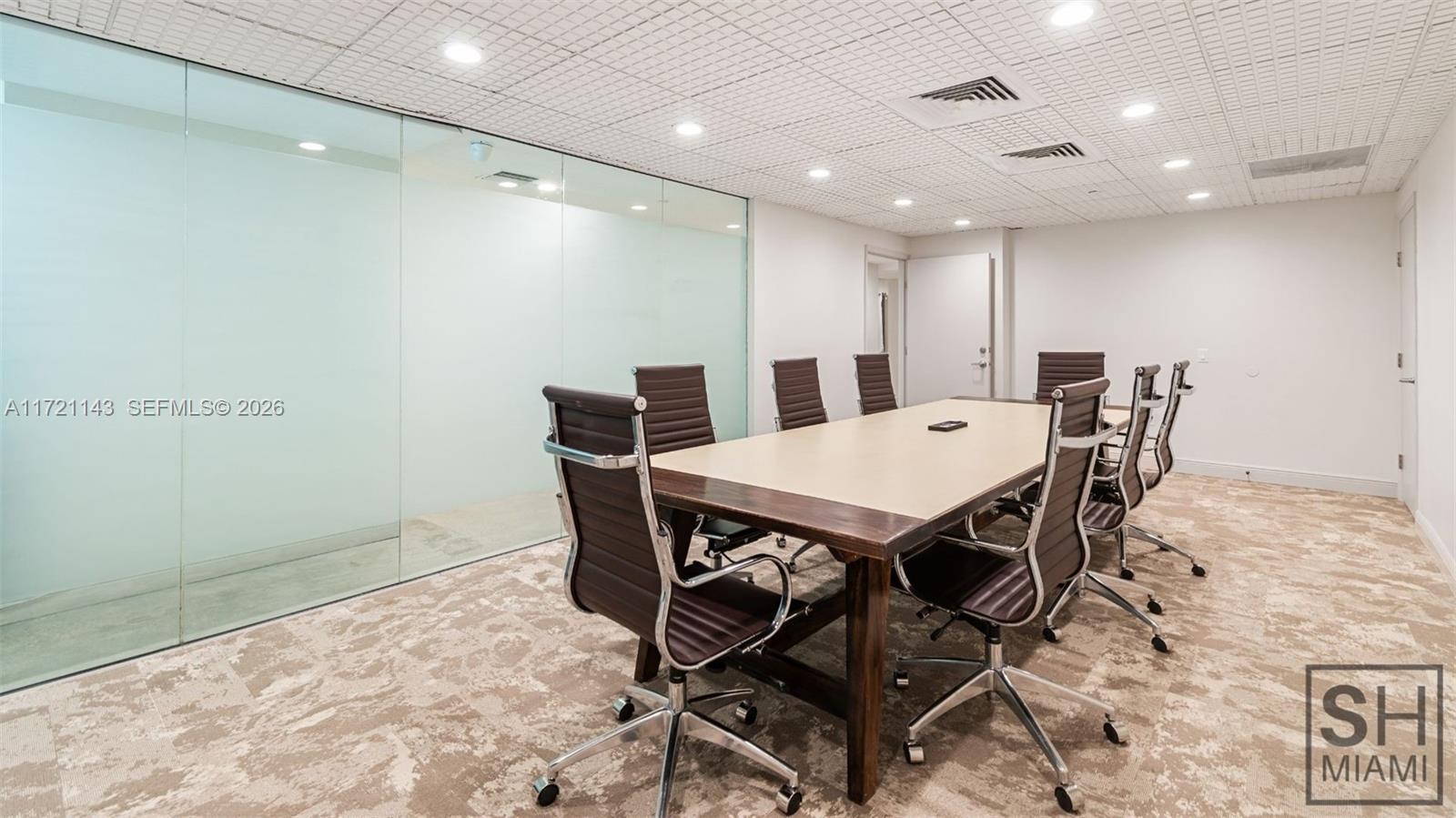 A conference room features a long table, rolling chairs, a glass wall, and patterned carpeting — 820 W 41 St # 401, Miami Beach FL 33140, MIAMI BEACH, FL