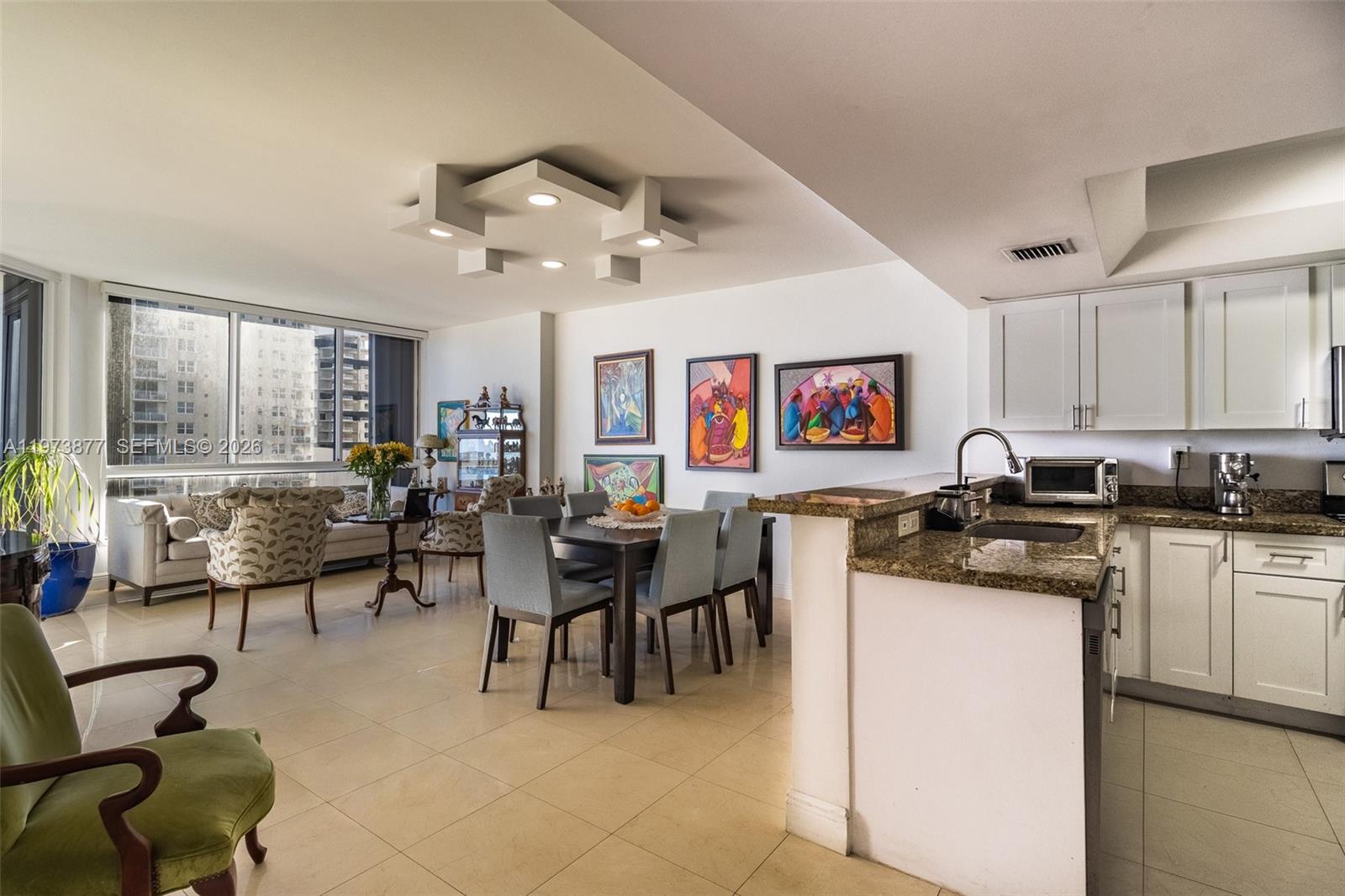 An open-concept living and dining area features tile floors, white cabinets, and a modern ceiling light — 520 Brickell Key Dr # A1007, Miami FL 33131, MIAMI, FL