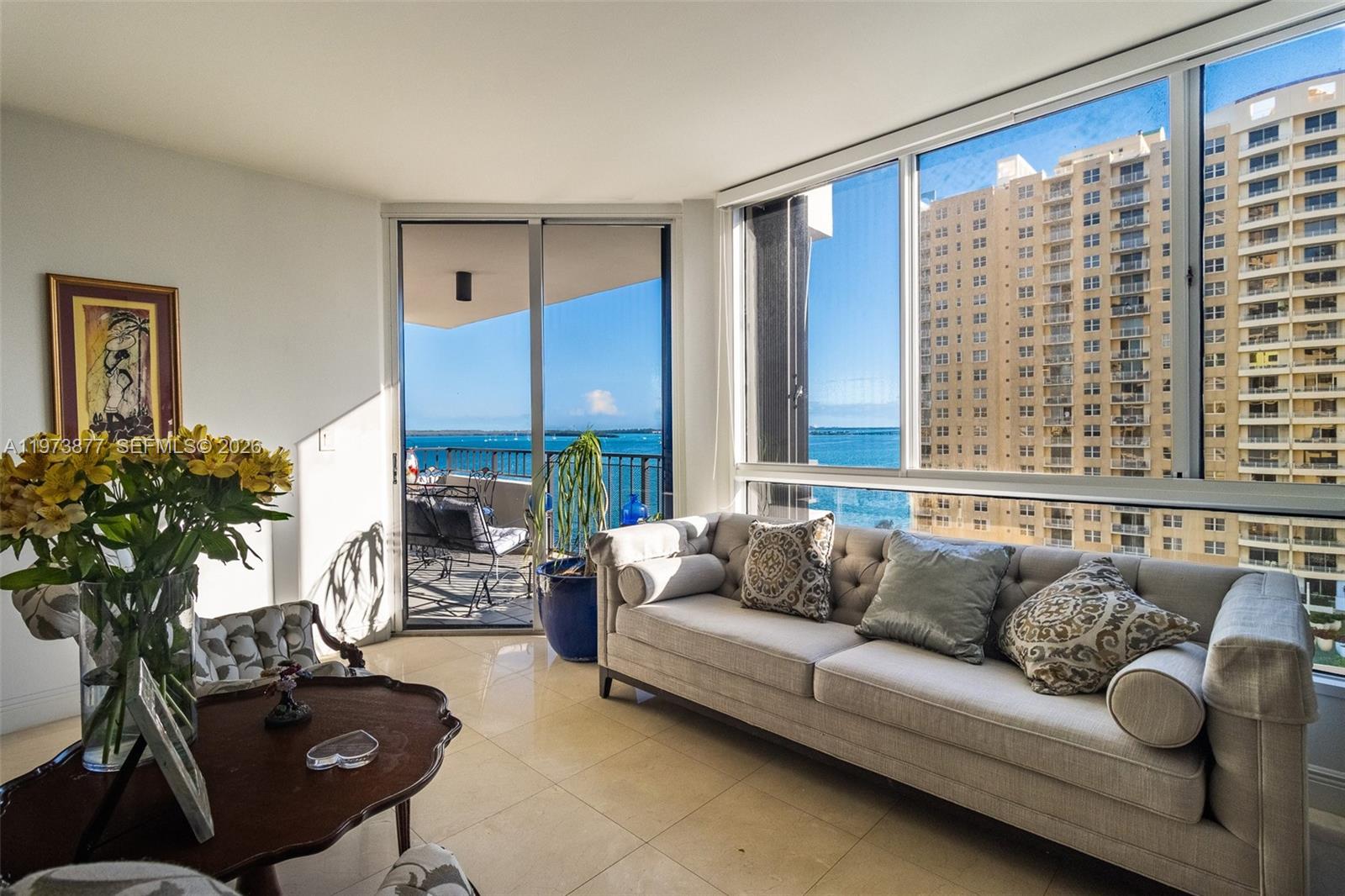 A living room features a tufted sofa, tile floors, and a balcony overlooking the ocean — 520 Brickell Key Dr # A1007, Miami FL 33131, MIAMI, FL
