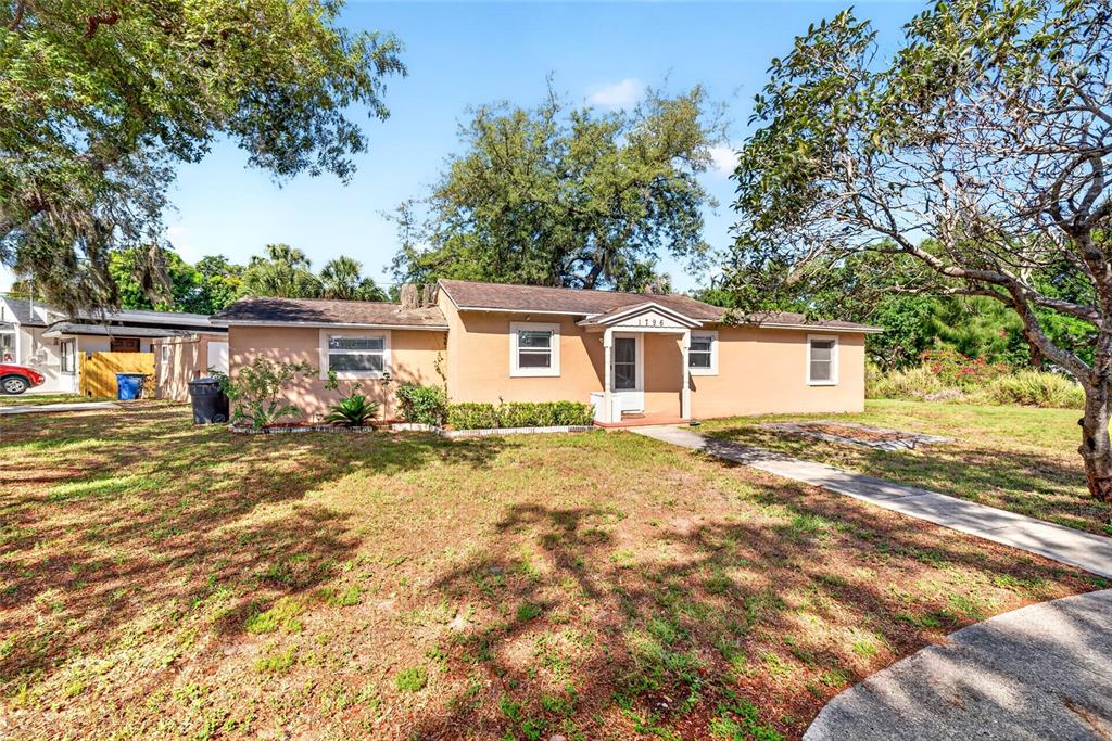 A single-story tan house with a brown roof sits on a grassy lot with trees — 1796 HARBOR DRIVE, CLEARWATER, FL