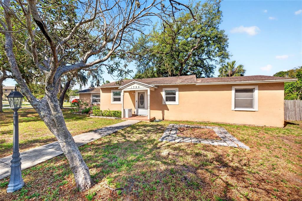A single-story tan house with a front walkway and a stone-bordered garden bed — 1796 HARBOR DRIVE, CLEARWATER, FL