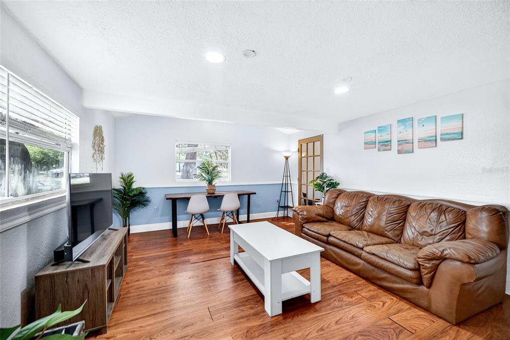 A living room features a brown leather sofa, white coffee table, and a dining table — 1796 HARBOR DRIVE, CLEARWATER, FL