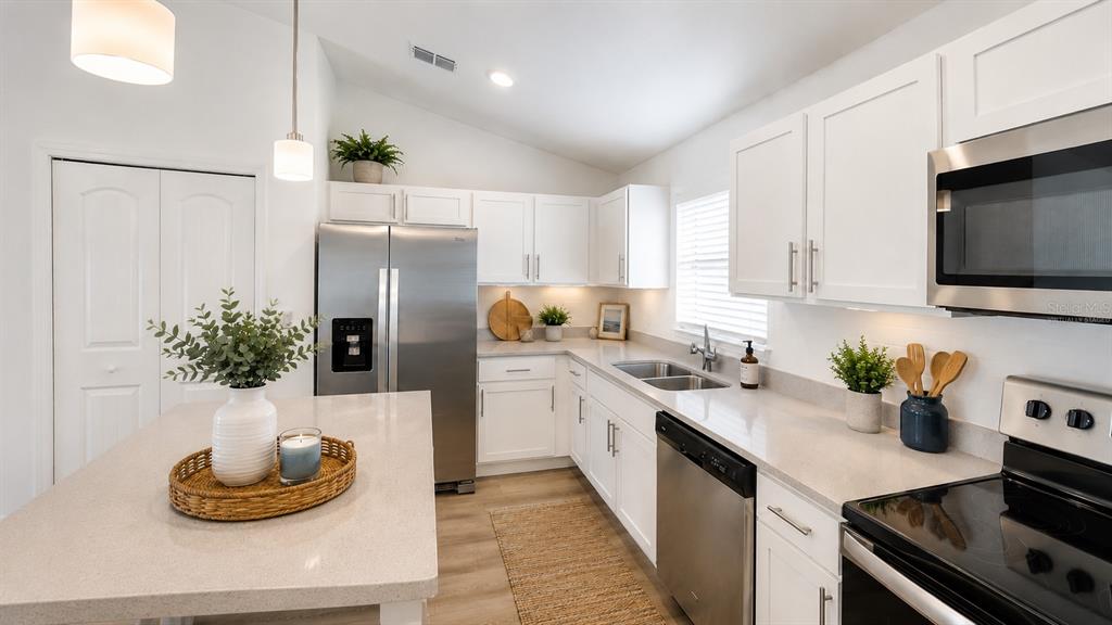 A modern kitchen features white cabinets, stainless steel appliances, and a central island with seating — 22 ZEBULAHS TRAIL, PALM COAST, FL
