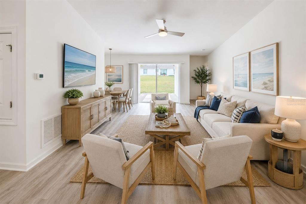 A bright living room with light wood flooring, a beige sofa, and a dining area — 22 ZEBULAHS TRAIL, PALM COAST, FL