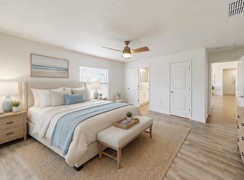 A bedroom with a king bed, light wood flooring, a ceiling fan, and neutral decor — 22 ZEBULAHS TRAIL, PALM COAST, FL