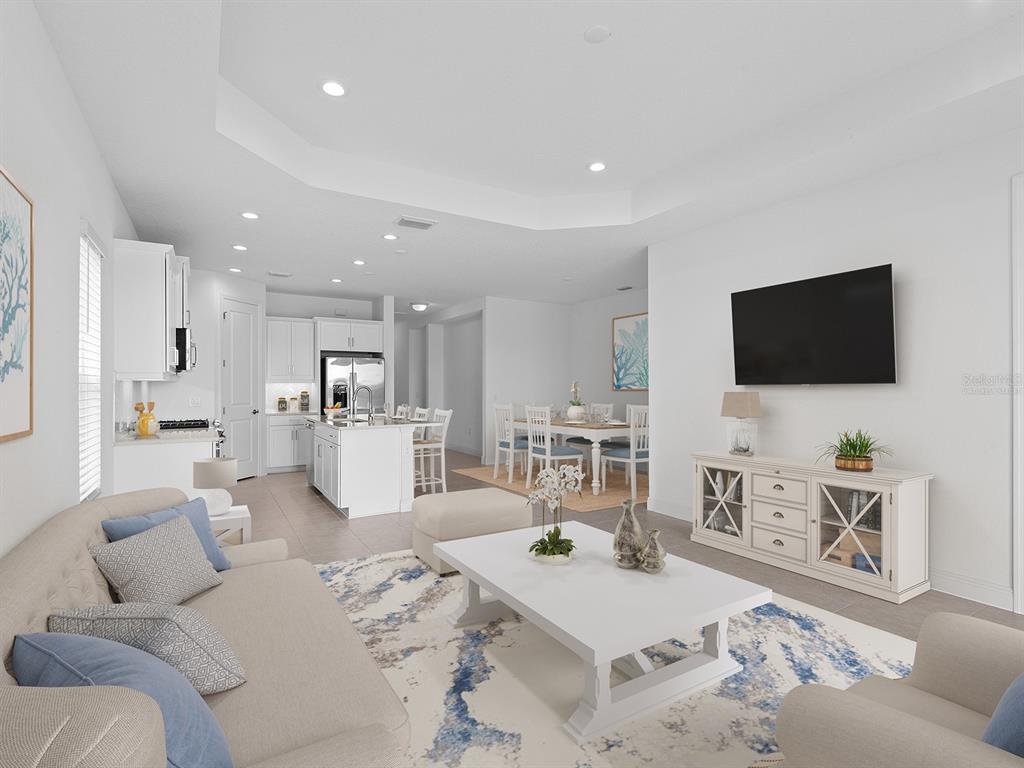 An open-concept living room and kitchen featuring white cabinetry, a central island, and tile flooring — 18260 VIZCAYA COURT, VENICE, FL