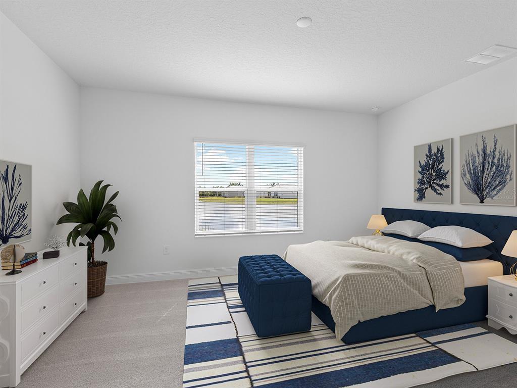A bedroom features a blue upholstered bed, a matching bench, a white dresser, and a window — 18260 VIZCAYA COURT, VENICE, FL