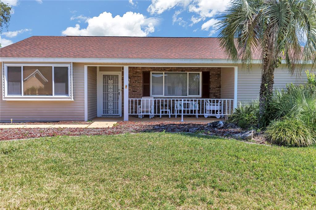 A single-story house with beige siding, a brick facade, and a covered front porch — 8157 SW 108TH STREET ROAD, OCALA, FL