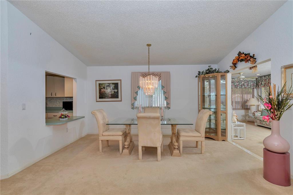 A dining room features a glass-topped table, beige upholstered chairs, and a crystal chandelier — 8157 SW 108TH STREET ROAD, OCALA, FL