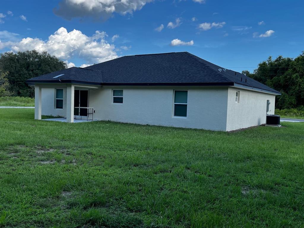 The exterior back view of a single-story house with a covered patio and lawn — 15200 SW 60TH CIRCLE, OCALA, FL