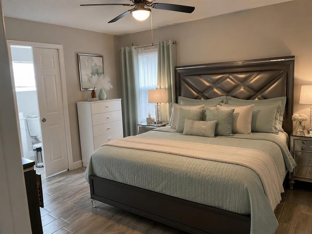 A bedroom features a tufted headboard, light blue bedding, a white dresser, and wood-look flooring — 15200 SW 60TH CIRCLE, OCALA, FL