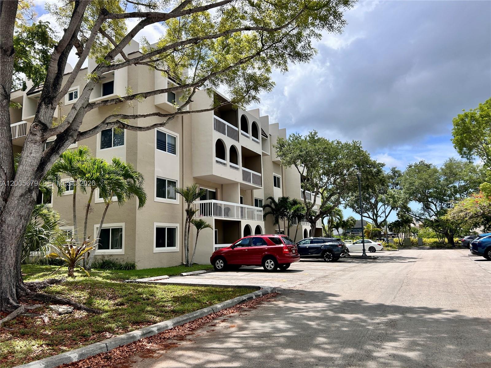 A multi-story apartment building with balconies and a parking lot in the foreground — 7740 Camino Real # G404, Miami FL 33143, MIAMI, FL
