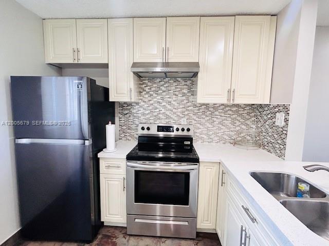 A kitchen features cream-colored cabinets, stainless steel appliances, and a mosaic tile backsplash — 7740 Camino Real # G404, Miami FL 33143, MIAMI, FL