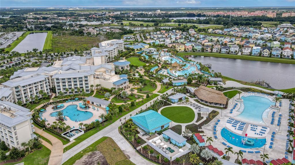 An aerial view shows a resort complex with multiple swimming pools, buildings, and a lake — 3151 SUNSET WALK DRIVE UNIT 112, KISSIMMEE, FL