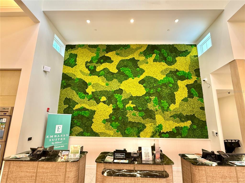 A hotel lobby features a large moss wall behind three reception desks — 3151 SUNSET WALK DRIVE UNIT 112, KISSIMMEE, FL