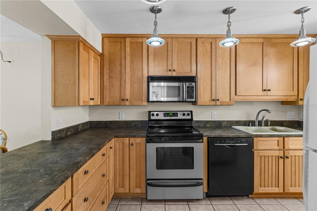 A kitchen features light wood cabinets, stainless steel appliances, and dark laminate countertops — 2851 SW 32ND AVENUE UNIT B6, OCALA, FL