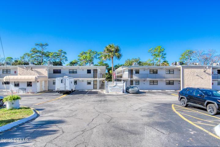 A two-story apartment complex with a parking lot and a palm tree in front — 1504 VIRGINIA AVENUE UNIT 101, DAYTONA BEACH, FL