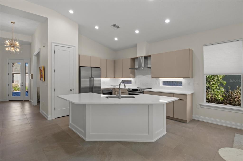 A modern kitchen features light-colored flat-panel cabinets, a white quartz island, and tile flooring — 7826 LAKE JAMES BOULEVARD, LAKELAND, FL