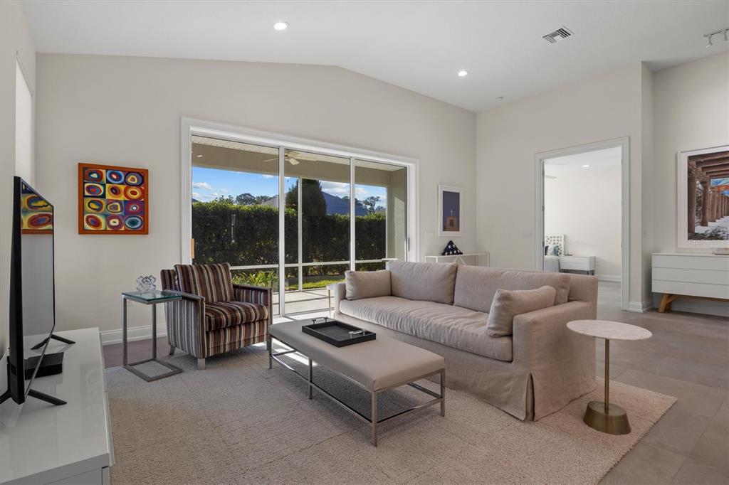 A living room features a beige sofa, a striped armchair, and a large sliding glass door — 7826 LAKE JAMES BOULEVARD, LAKELAND, FL