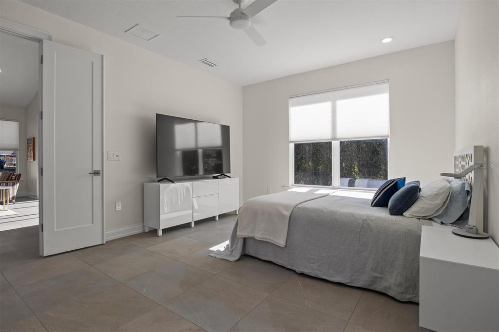 A bedroom features tile flooring, a white media console with a television, and a bed — 7826 LAKE JAMES BOULEVARD, LAKELAND, FL