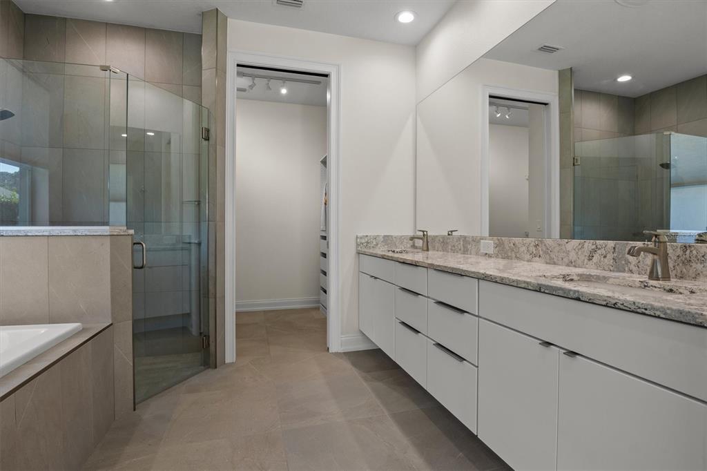 A modern bathroom features a floating vanity, a glass-enclosed shower, and a walk-in closet — 7826 LAKE JAMES BOULEVARD, LAKELAND, FL