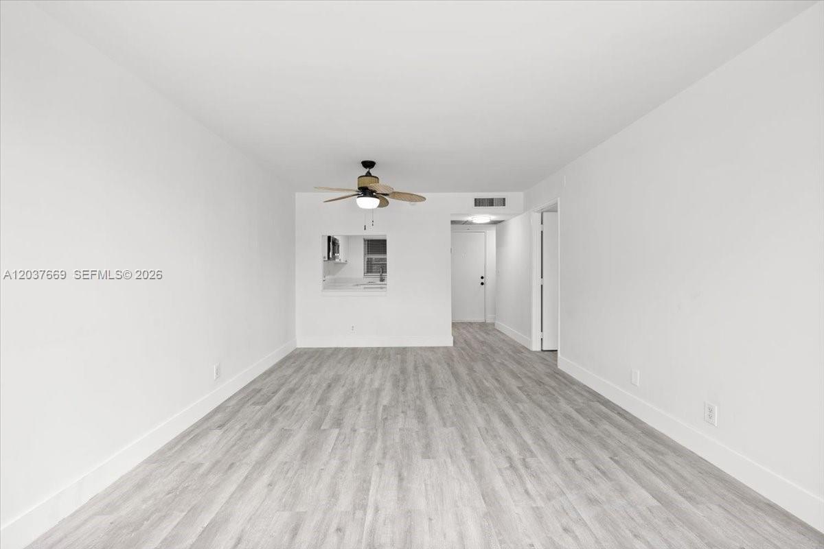 A bright, empty living room features light gray wood-look flooring and a ceiling fan — 9441 Evergreen Pl # 206, Davie FL 33324, DAVIE, FL