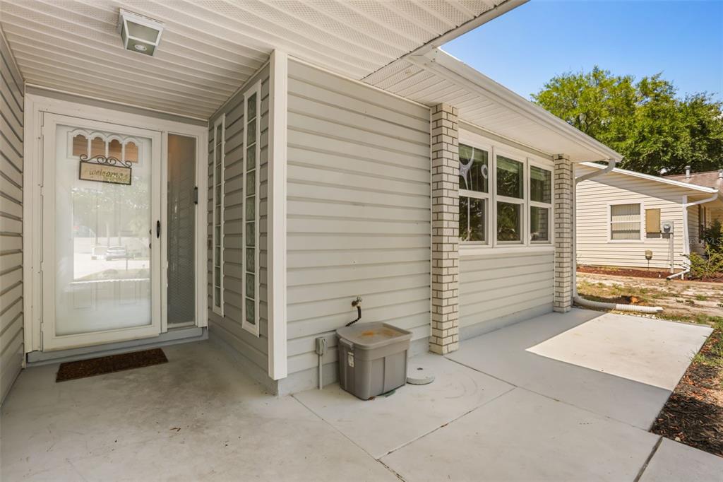 A concrete porch leads to a front door with a glass storm door and siding — 1305 MORAY COURT, LEESBURG, FL