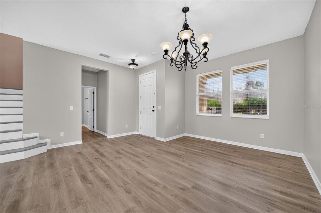 An empty room with gray walls, wood-look flooring, a chandelier, and a staircase — 1215 ALAPAHA LANE, ORLANDO, FL