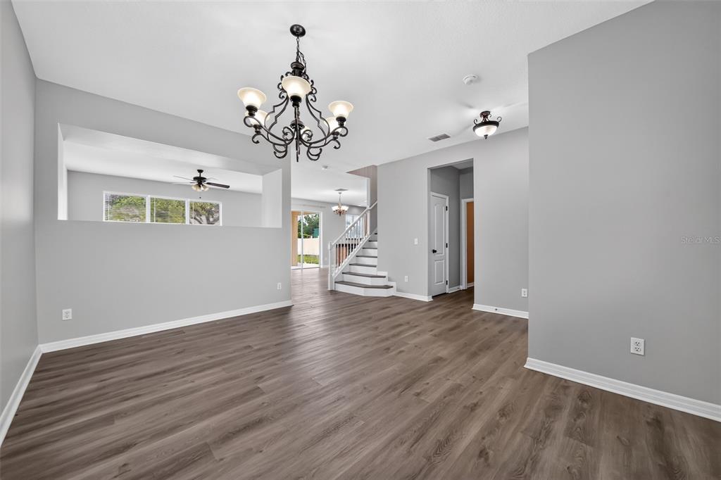 A dining area with wood-look flooring, a chandelier, and a staircase leading to the upper level — 1215 ALAPAHA LANE, ORLANDO, FL