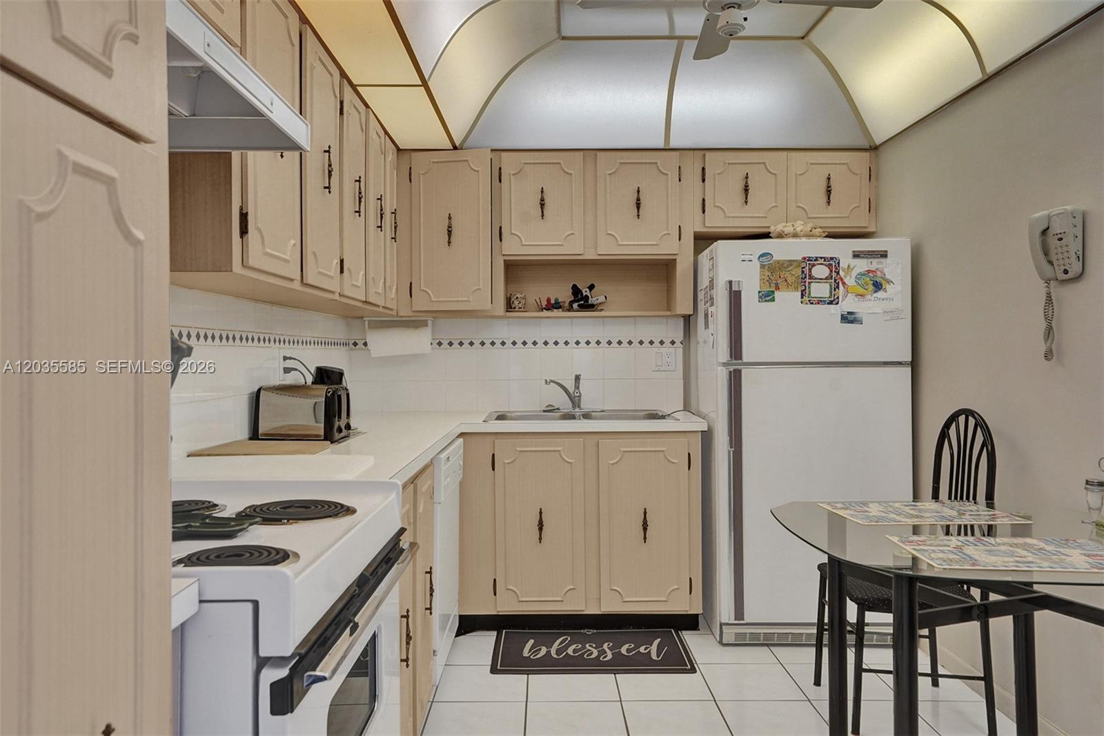 A kitchen features light-colored cabinetry, white appliances, a tiled backsplash, and a small dining table — 3113 S Ocean Dr # 803, Hallandale Beach FL 33009, HALLANDALE BEACH, FL