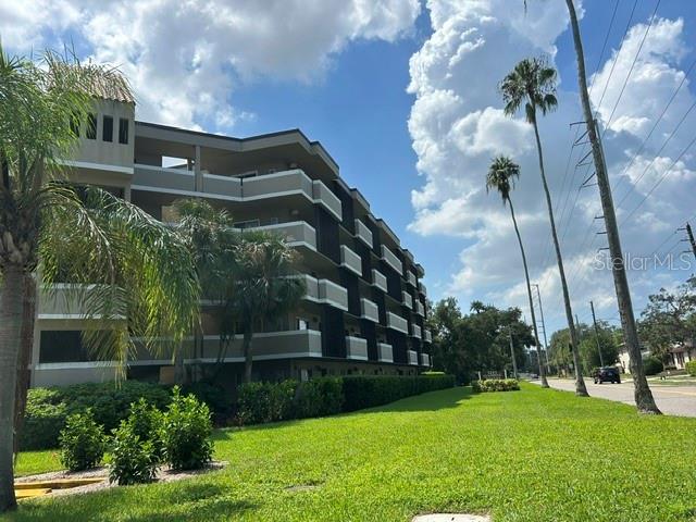 A multi-story apartment building stands next to a grassy lawn and tall palm trees — 1243 S MARTIN LUTHER KING JR AVENUE UNIT A401, CLEARWATER, FL