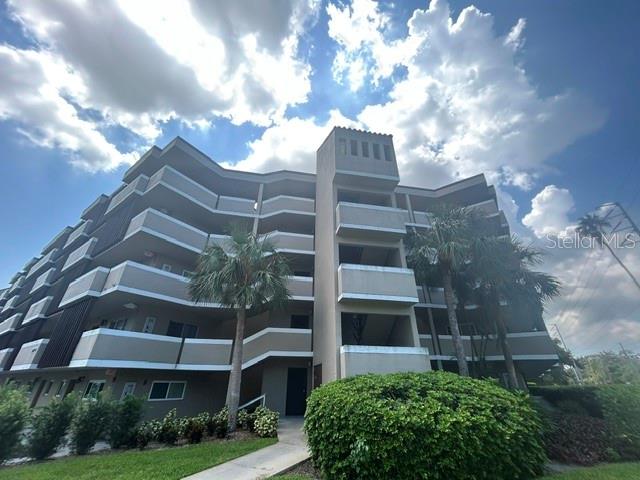 A multi-story apartment building with balconies and palm trees under a cloudy blue sky — 1243 S MARTIN LUTHER KING JR AVENUE UNIT A401, CLEARWATER, FL