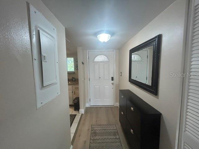 An entryway features light wood-look flooring, a black shoe cabinet, a wall mirror, and a door — 1243 S MARTIN LUTHER KING JR AVENUE UNIT A401, CLEARWATER, FL