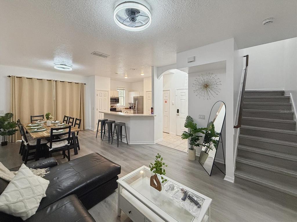 A living room features a black sectional sofa, a white coffee table, and a gallery wall — 1302 S BEACH CIRCLE, KISSIMMEE, FL