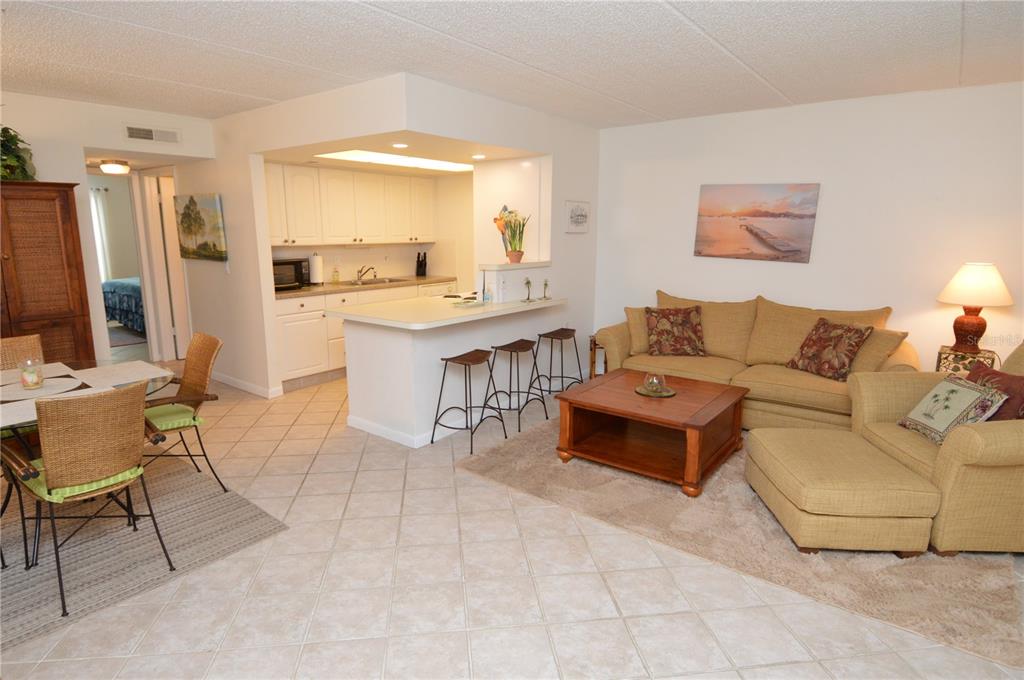 An open-concept living room and kitchen featuring tile floors, a breakfast bar, and beige furniture — 12760 INDIAN ROCKS ROAD UNIT 553, LARGO, FL