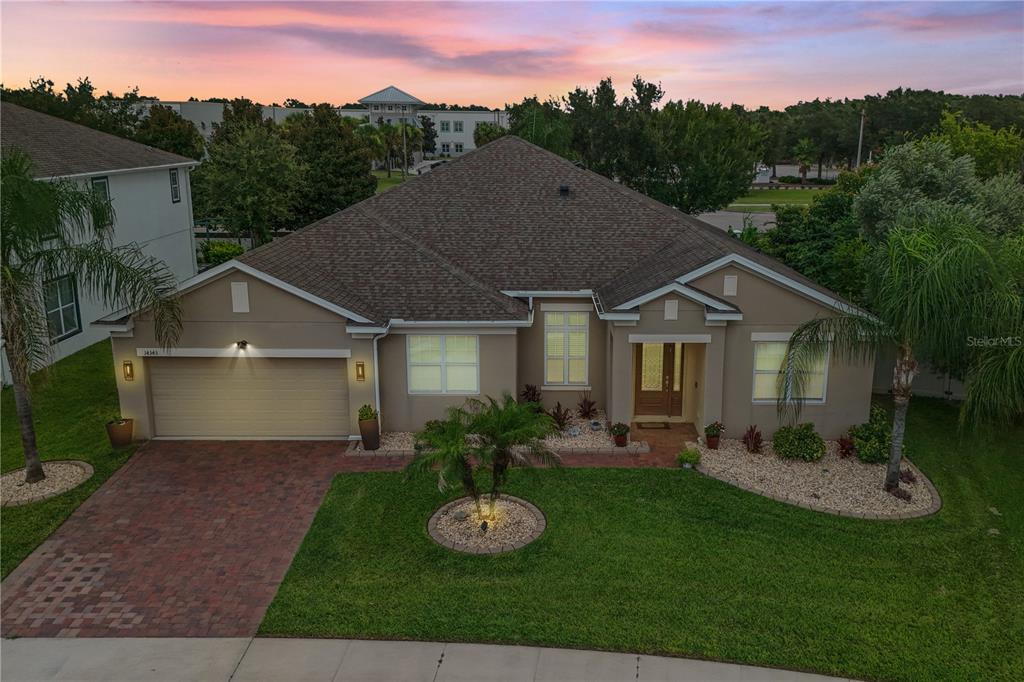 A single-story suburban house with a tan stucco exterior, shingled roof, and paved driveway — 14343 BLACK LAKE PRESERVE STREET, WINTER GARDEN, FL