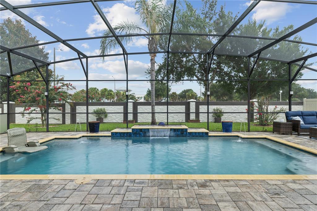 A swimming pool with a waterfall feature is enclosed by a screened lanai and patio — 14343 BLACK LAKE PRESERVE STREET, WINTER GARDEN, FL