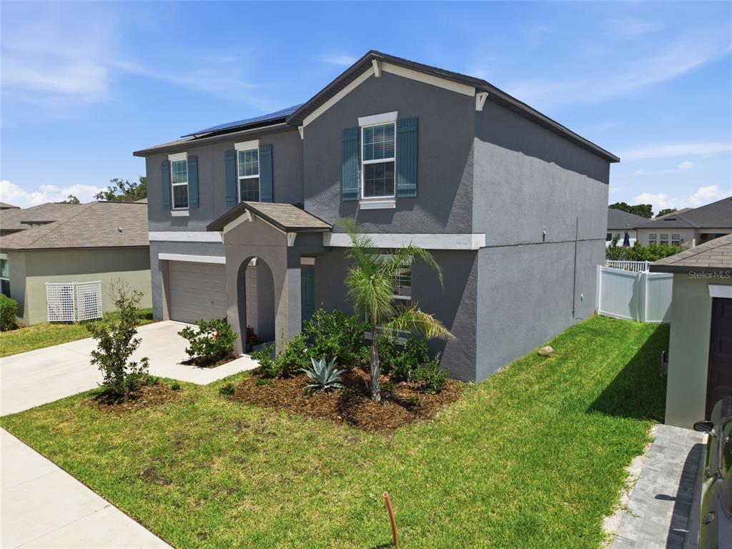 A two-story gray house with a front-facing garage and a small arched entryway — 13380 GREAT PLAINS DRIVE, RIVERVIEW, FL