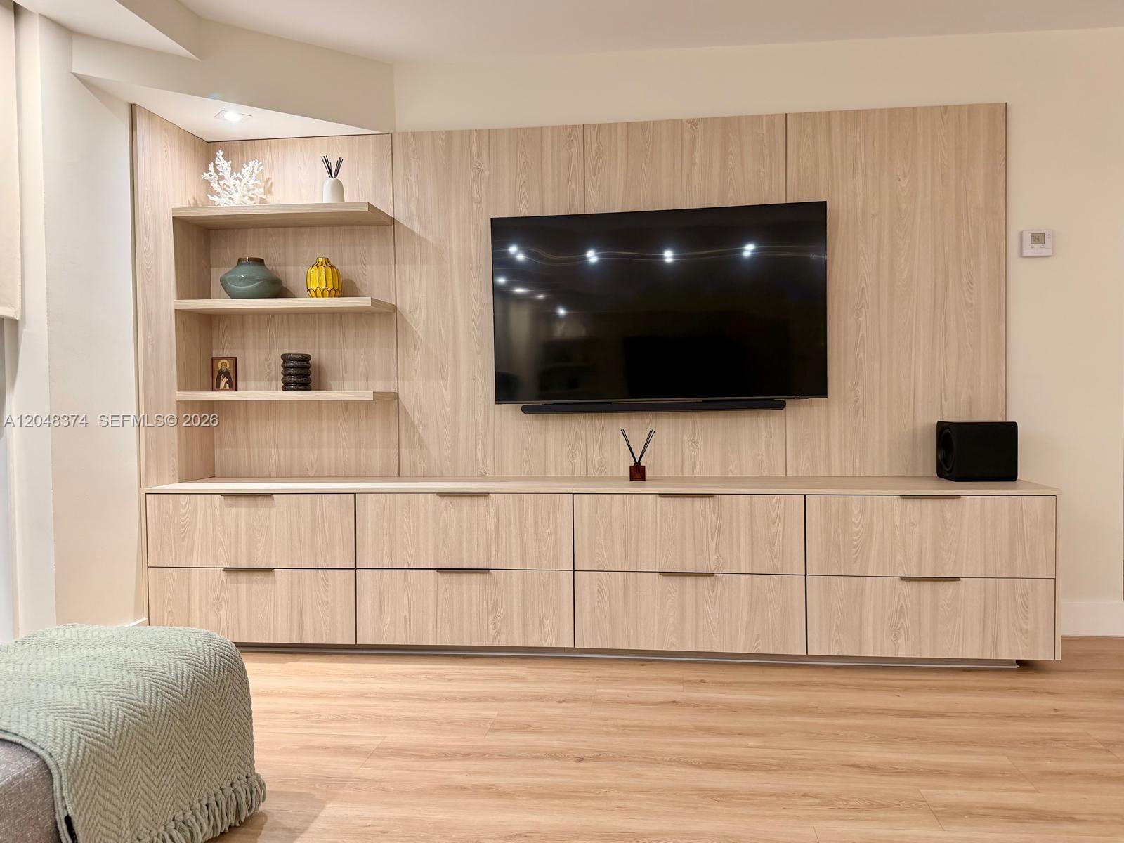 A living room features a light wood media console with built-in shelving and a wall-mounted television — 10275 Collins Ave # 333, Bal Harbour FL 33154, BAL HARBOUR, FL