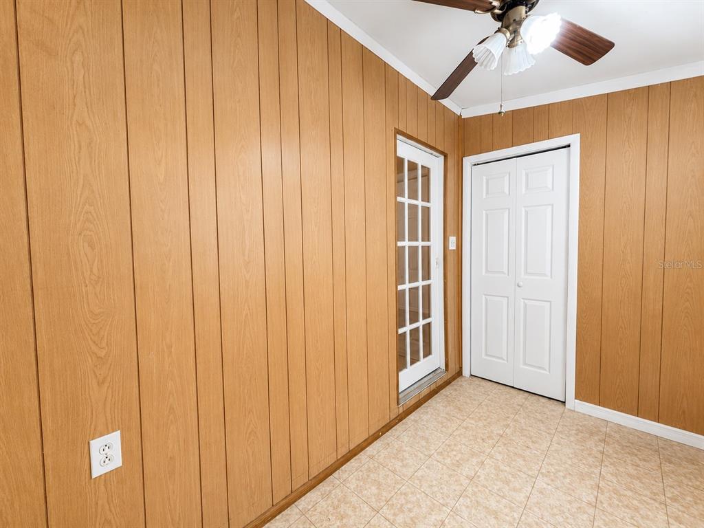 A room with wood-paneled walls, tile flooring, a ceiling fan, a glass door, and closet — 2910 WESTERN WILLOW TERRACE, ORLANDO, FL