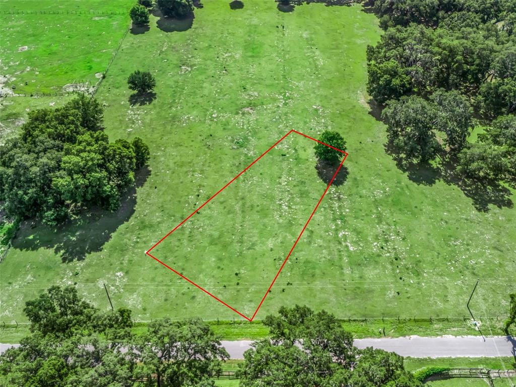 An aerial view shows a rectangular plot of land outlined in red in a field — Lot 20 CR 543, BUSHNELL, FL