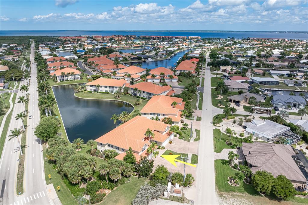 An aerial view shows a residential complex with orange-tiled roofs next to a lake — 197 TROPICANA DRIVE UNIT 1511, PUNTA GORDA, FL
