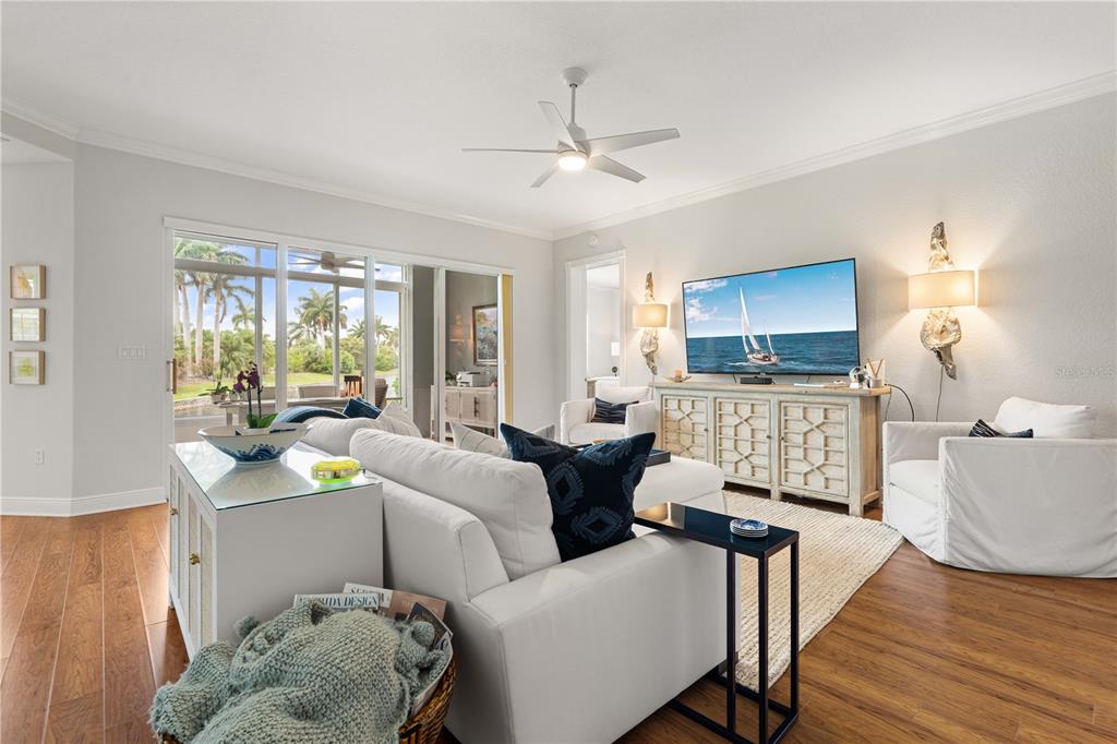 A bright living room features a white sofa, a television, and sliding glass doors to a patio — 197 TROPICANA DRIVE UNIT 1511, PUNTA GORDA, FL