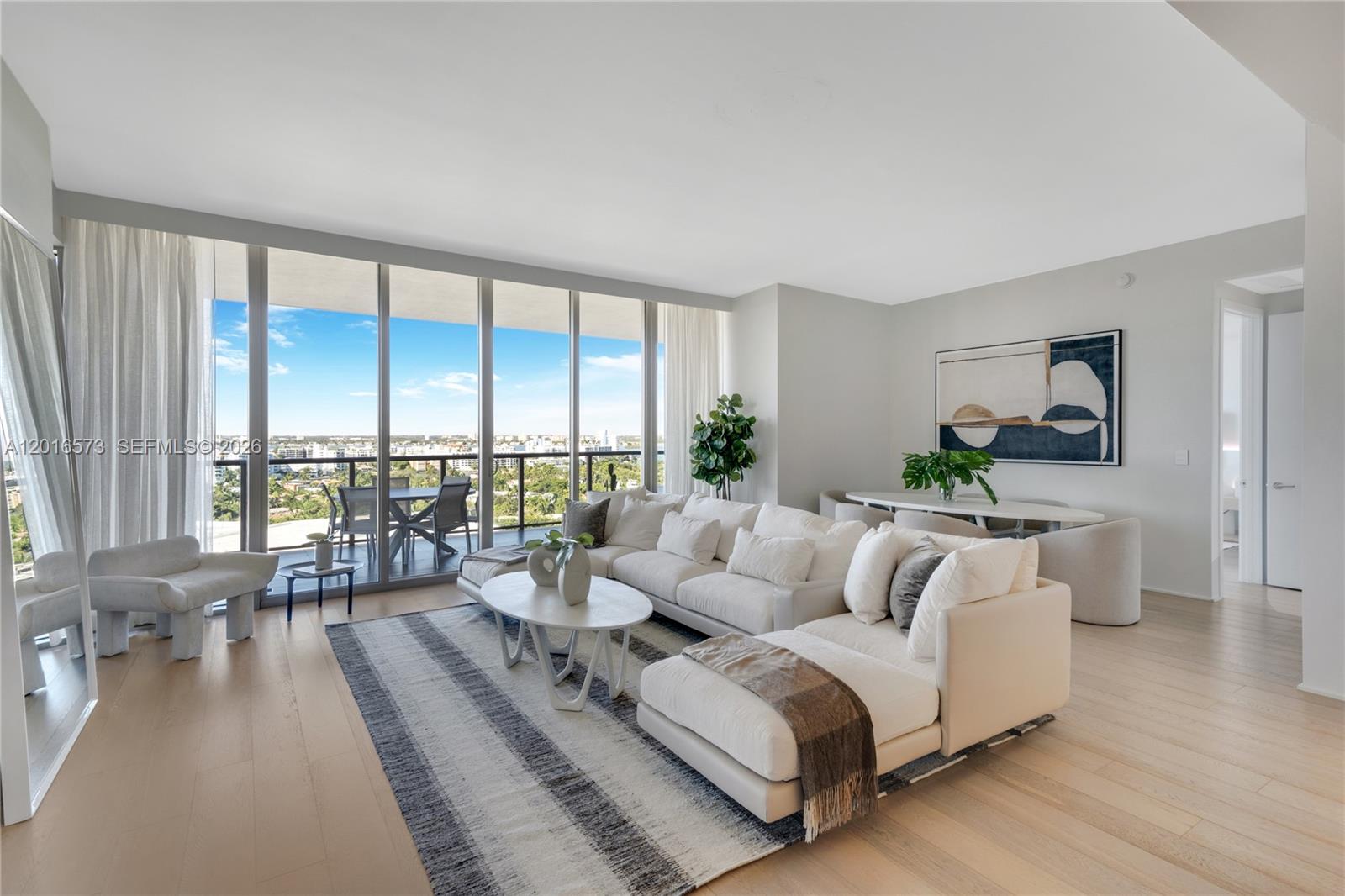 A bright living room features a white sectional sofa, a striped rug, and floor-to-ceiling windows — 9705 Collins Ave # 1205N, Bal Harbour FL 33154, BAL HARBOUR, FL