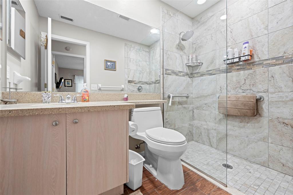 A bathroom features a light wood vanity, a white toilet, and a tiled walk-in shower — 2552 CRYSTAL LAKE DRIVE, SPRING HILL, FL