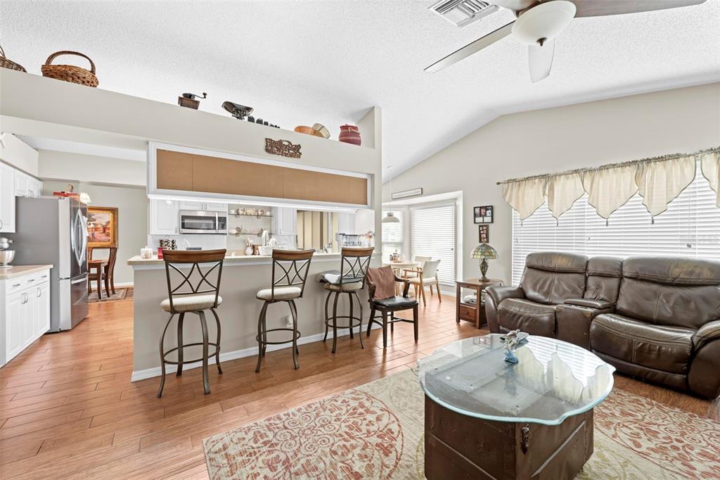 A living room with a breakfast bar, brown leather sofa, and wood-look flooring — 2552 CRYSTAL LAKE DRIVE, SPRING HILL, FL