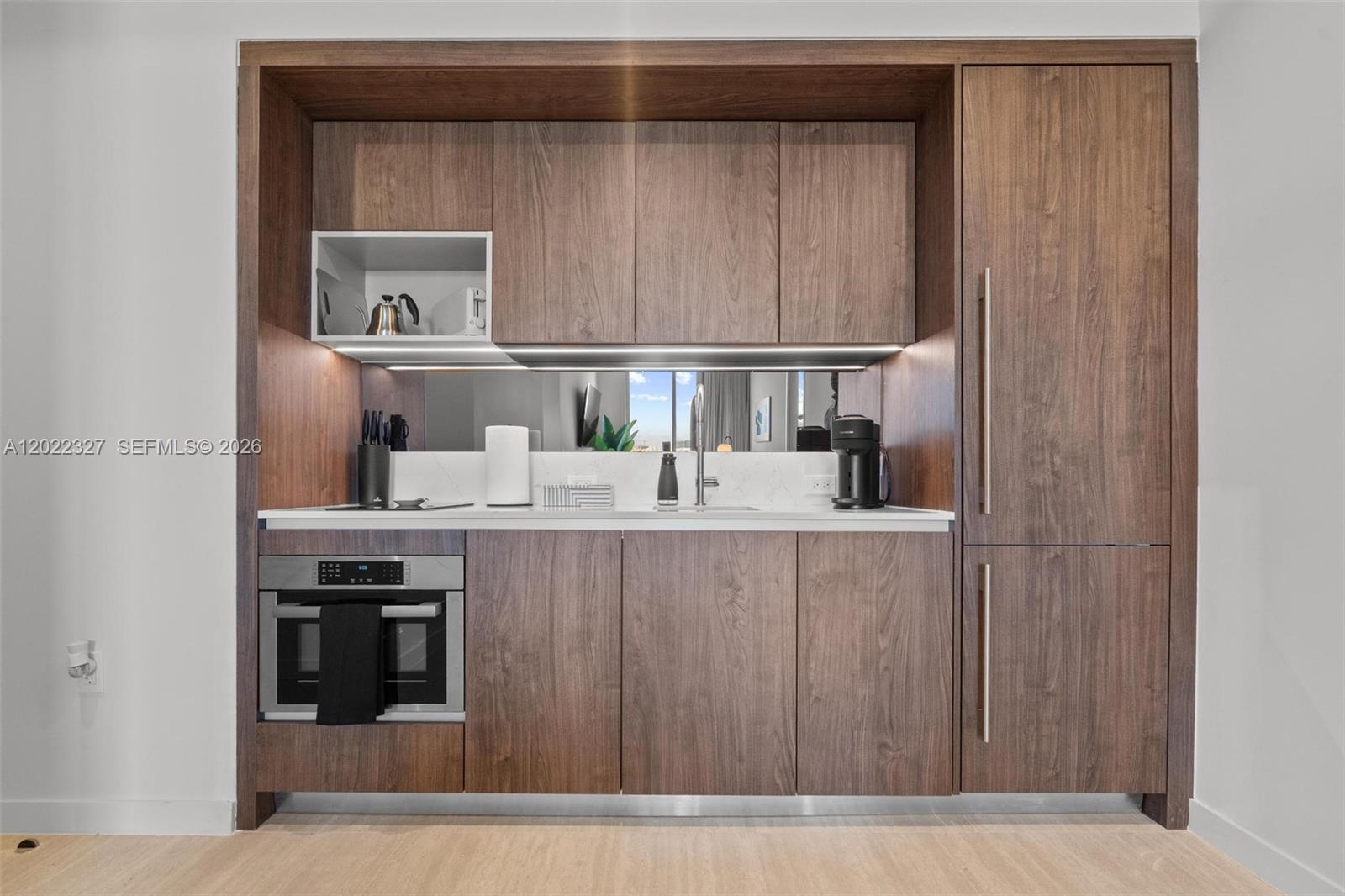 A modern kitchenette features wood-grain cabinetry, a built-in microwave, and a mirrored backsplash — 1611 SW 2nd Ave # 817, Miami FL 33129, MIAMI, FL
