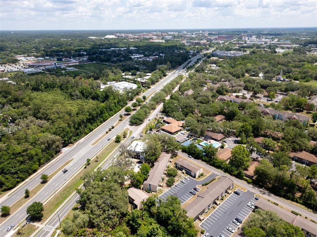 An aerial view shows a multi-lane road running through a wooded area with apartment complexes — 2811 SW ARCHER ROAD UNIT C18, GAINESVILLE, FL
